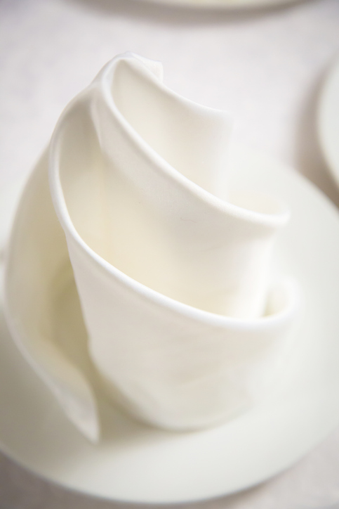 Beautiful white swirling napkin on a white plate